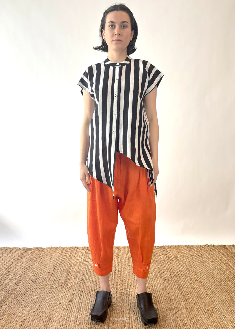 Person wearing a black and white striped shirt and orange pants on a plain background