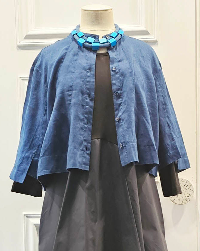 Mannequin wearing a blue jacket over a black dress in a store setting